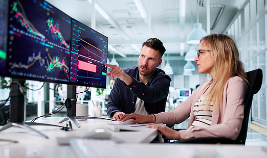 Zwei Personen analysieren Krypto-Daten auf dem Bildschirm