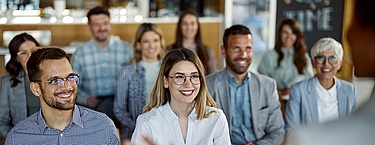 Sitzendes Publikum hört der Speakerin bei einer Konferenz zu