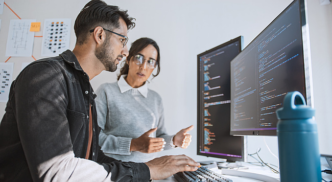 Zwei Mitarbeitende diskutieren den Programmcode einer KI-Lösung