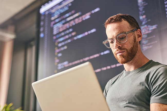 Krypto: Bankfachmann sieht sich Programmcode auf dem Laptop an