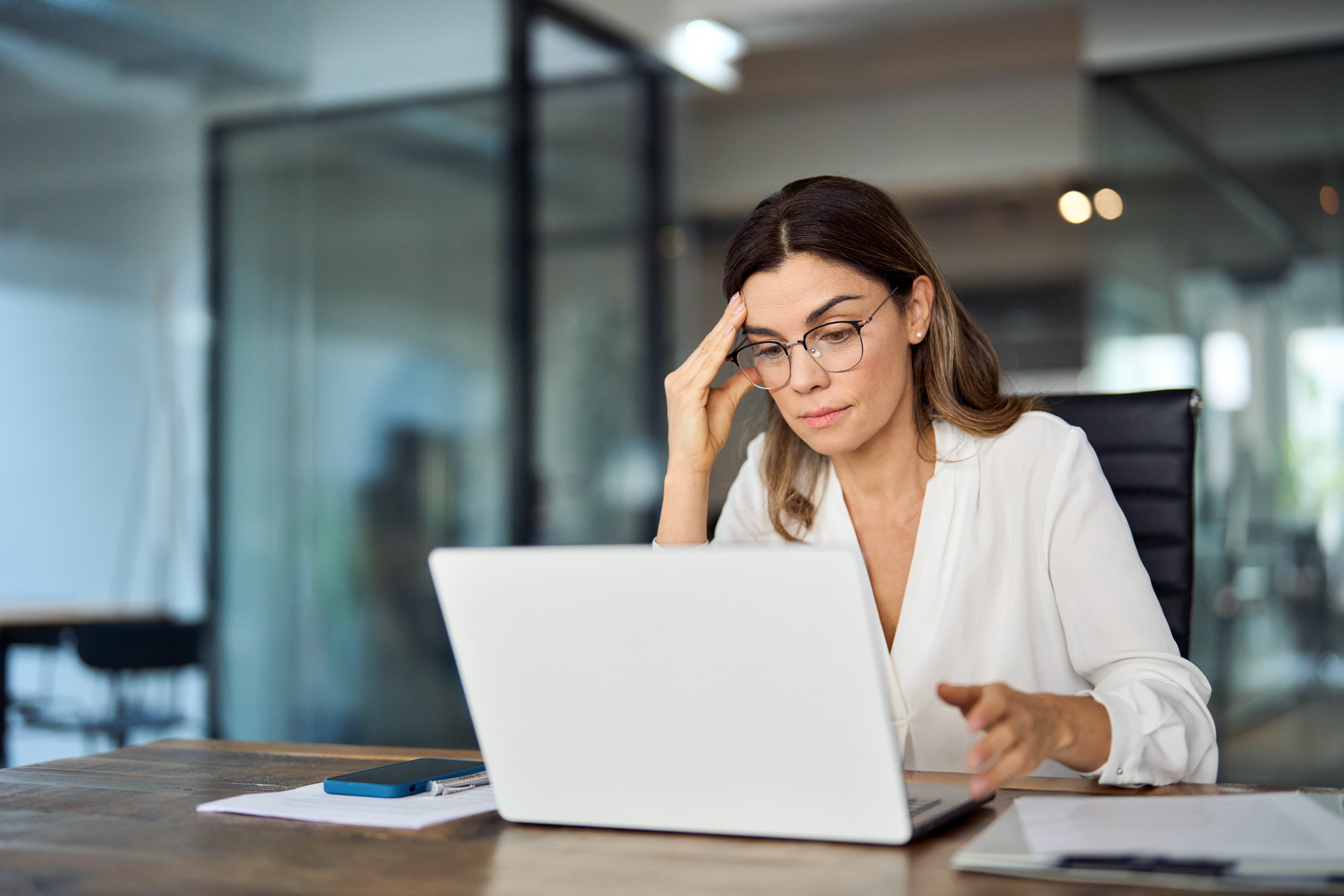 Business-Frau sitzt vor dem Laptop und stützt sichtlich gestresst ihren Kopf Business-Frau sitzt vor dem Laptop und stützt sichtlich gestresst ihren Kopf